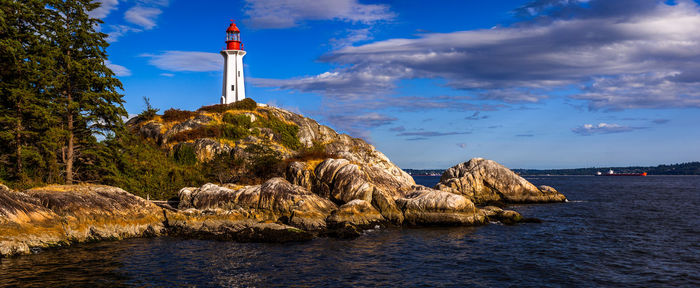 Lighthouse by sea against sky