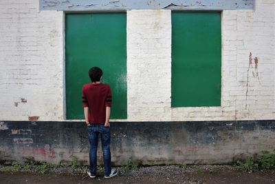 Full length of teenage boy standing against brick wall