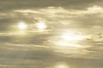 Low angle view of sunlight streaming through clouds