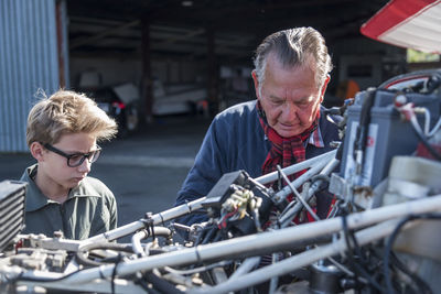 Germany, dierdorf, grandfather and grandson repairing biplane