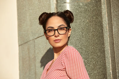 Portrait of young woman standing against wall