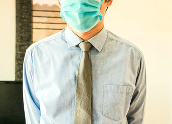 Midsection of man wearing mask standing against white background