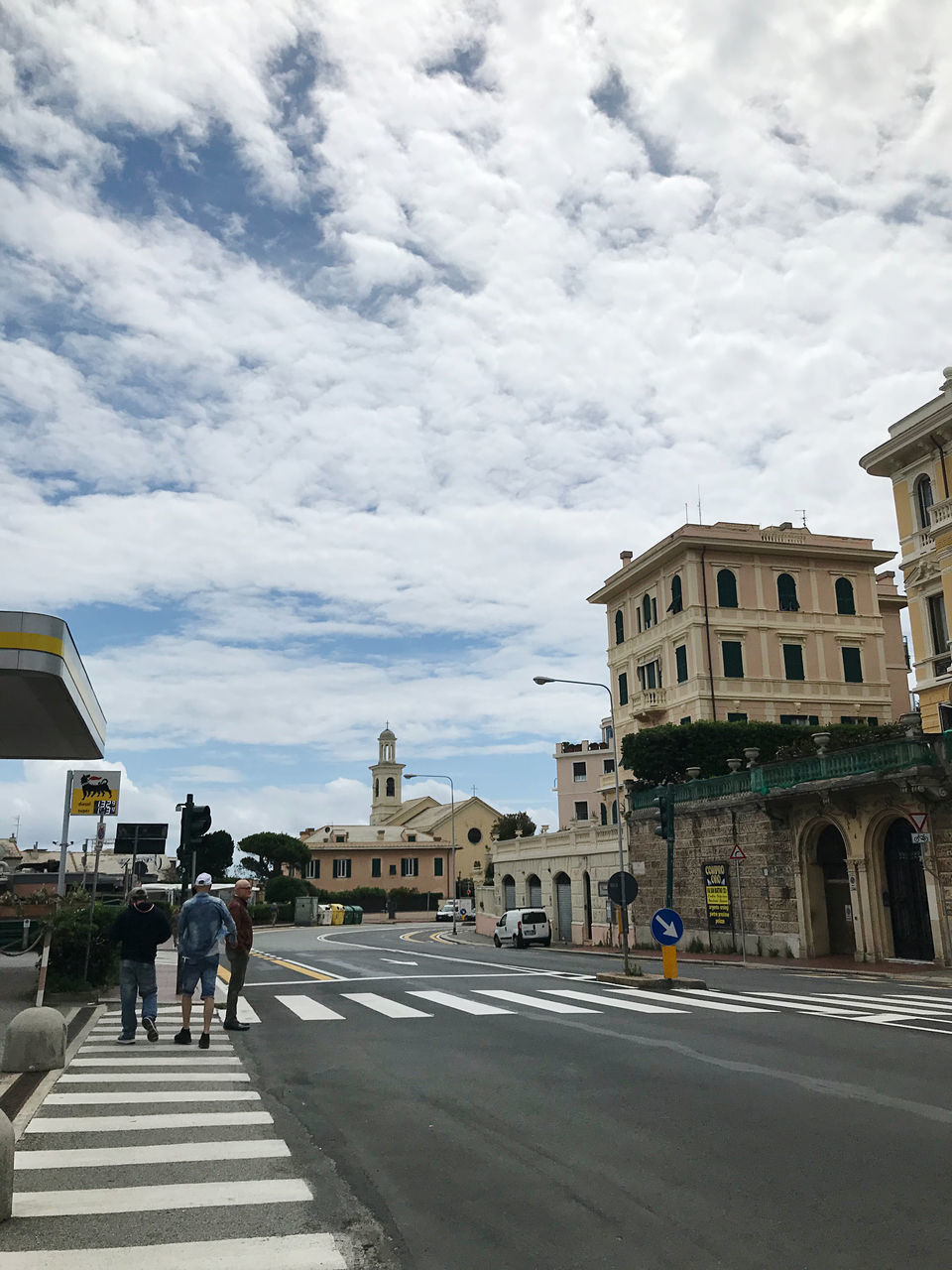 PEOPLE WALKING ON ROAD BY BUILDINGS AGAINST SKY