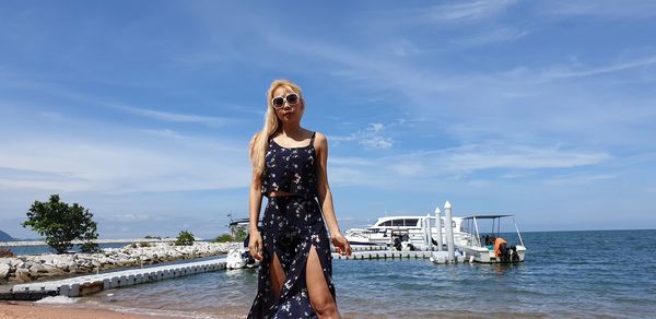 Young woman standing on sea against sky