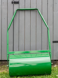 Lawn roller parked by grey wooden shed