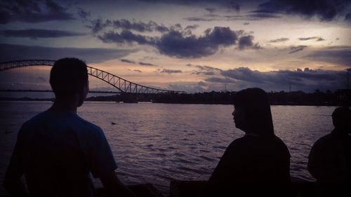 Silhouette people on bridge against sky during sunset