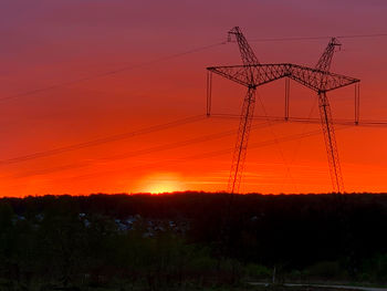 Silhouette electricity pylon on field against romantic sky at sunset