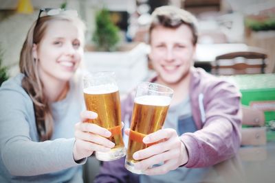 Portrait of young friends holding beer glasses at bar