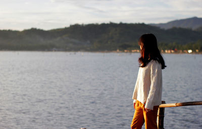 Rear view of woman standing in sea against sky