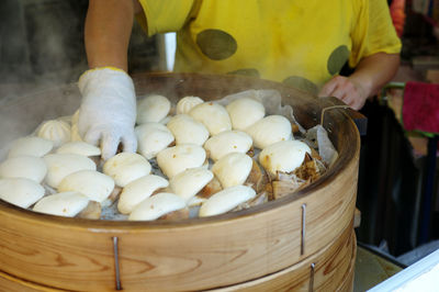 Selective focus of chinese steamed buns in the wooden steamer with seller in background