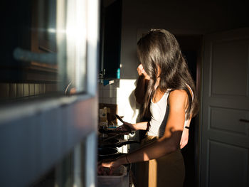 Side view of woman standing at home