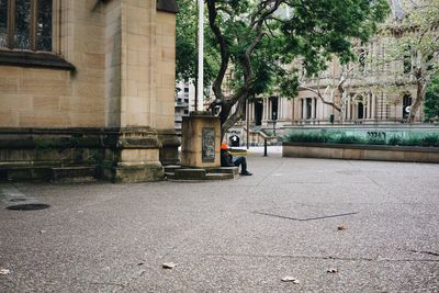 Person sitting against buildings in city