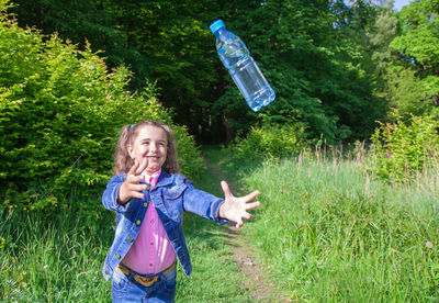 Smiling girl playing with water bottle in park