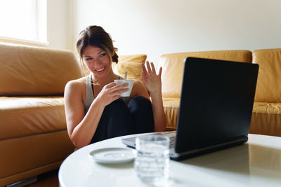 Young woman using mobile phone while sitting on sofa