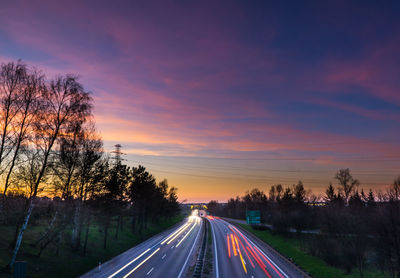 Cars on road against sky during sunset