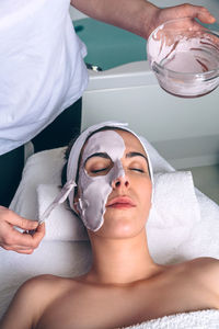 Beautician applying facial pack on customer face at spa