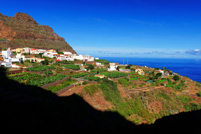 Town on mountain by sea against blue sky