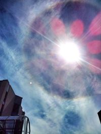 Low angle view of sun shining through clouds