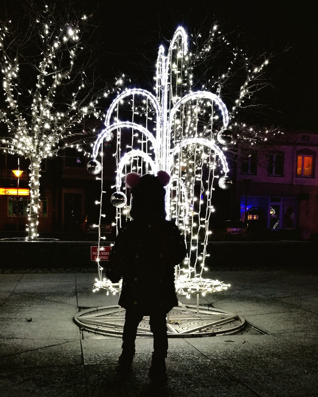 night, illuminated, real people, building exterior, one person, architecture, built structure, motion, street, rear view, standing, outdoors, full length, long exposure, lifestyles, tree, city, people