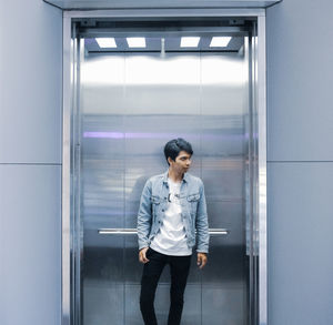 Full length of woman standing against glass wall