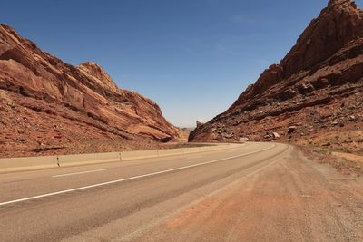 Landscape of road leading down through vertical red rock formations in the san rafael swell in utah