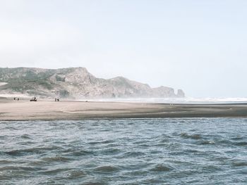 Scenic view of sea and mountains against clear sky