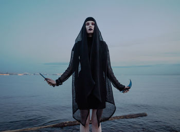 Young woman standing in sea against sky