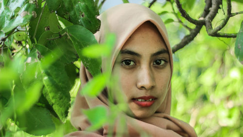 Portrait of young woman against plants