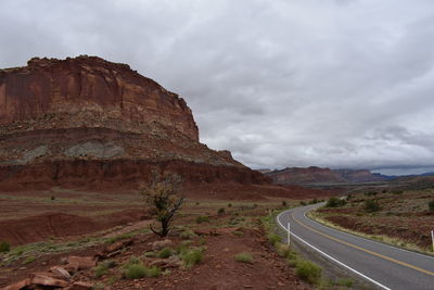 Road leading towards rock formation against sky