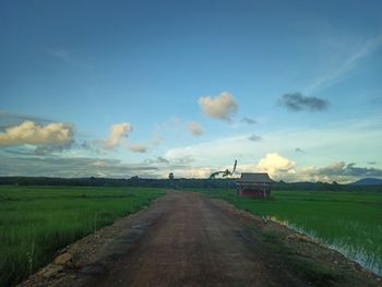 Road amidst field against sky