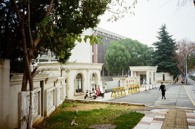 People walking by historic building against sky