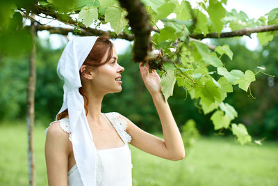 Portrait of young woman standing against plants