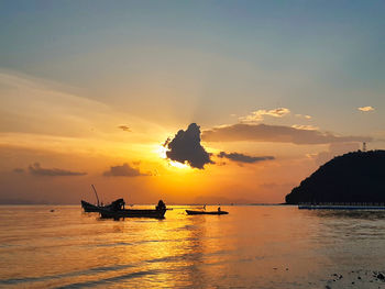 Silhouette boats in sea against sky during sunset