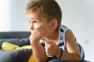 Boy looking away while sitting on sofa