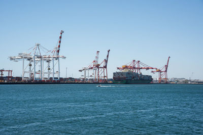 Cranes at commercial dock against clear sky