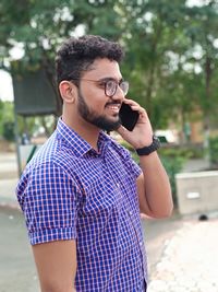 Young man wearing sunglasses standing against blurred background