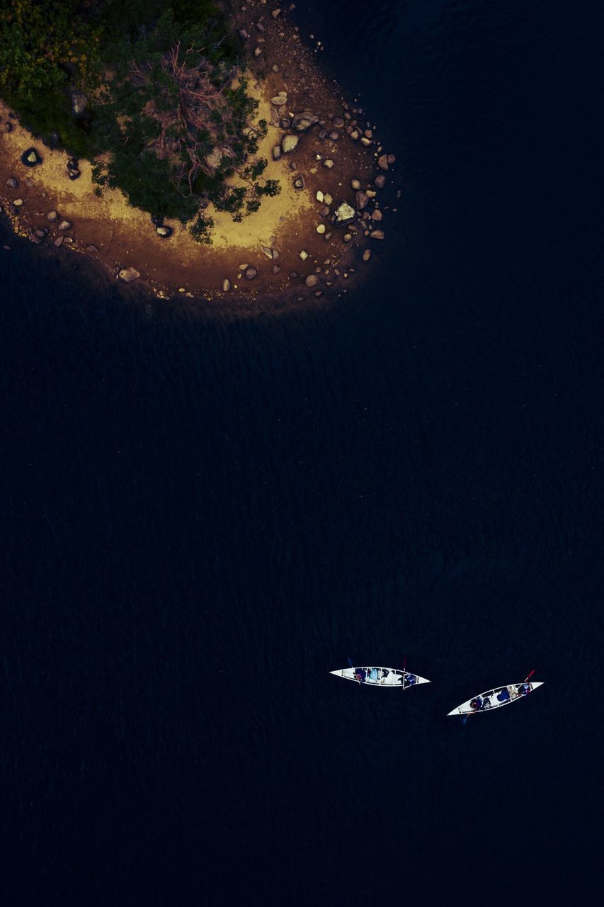 HIGH ANGLE VIEW OF AIRPLANE FLYING ABOVE SEA AT NIGHT