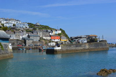 Buildings by sea against blue sky