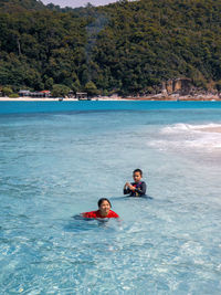Children swimming at the beach together in a sunny day.