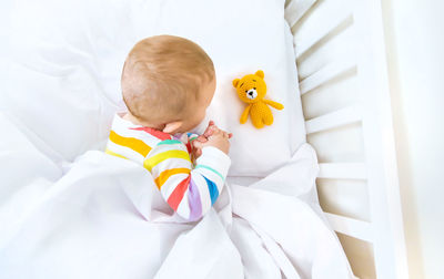 High angle view of baby girl lying on bed