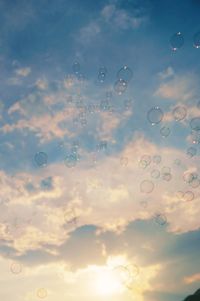 Low angle view of bubbles against rainbow in sky