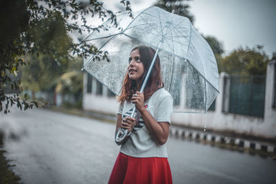 Woman holding umbrella while standing on rainy day