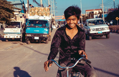 Portrait of smiling man riding bicycle on city street