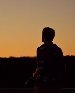 Rear view of woman standing at sunset