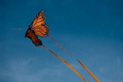 Low angle view of butterfly flying against blue sky