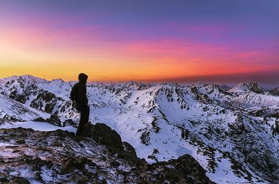 Silhouette person standing on snow covered landscape against sky