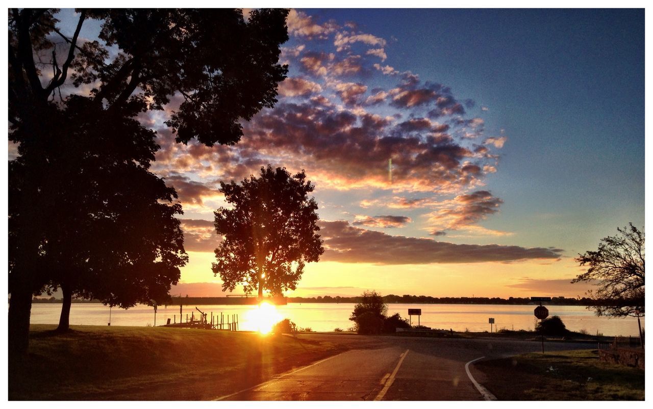 sun, sky, sunset, tree, transfer print, cloud - sky, transportation, car, sunbeam, sunlight, land vehicle, silhouette, water, auto post production filter, scenics, nature, lens flare, beauty in nature, road, tranquil scene