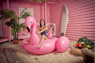 Full length of woman wearing bikini sitting on pool raft at beach