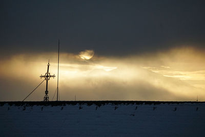 Low angle view of silhouette cranes against sky at sunset