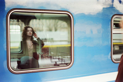 A woman stands near a train at a train station